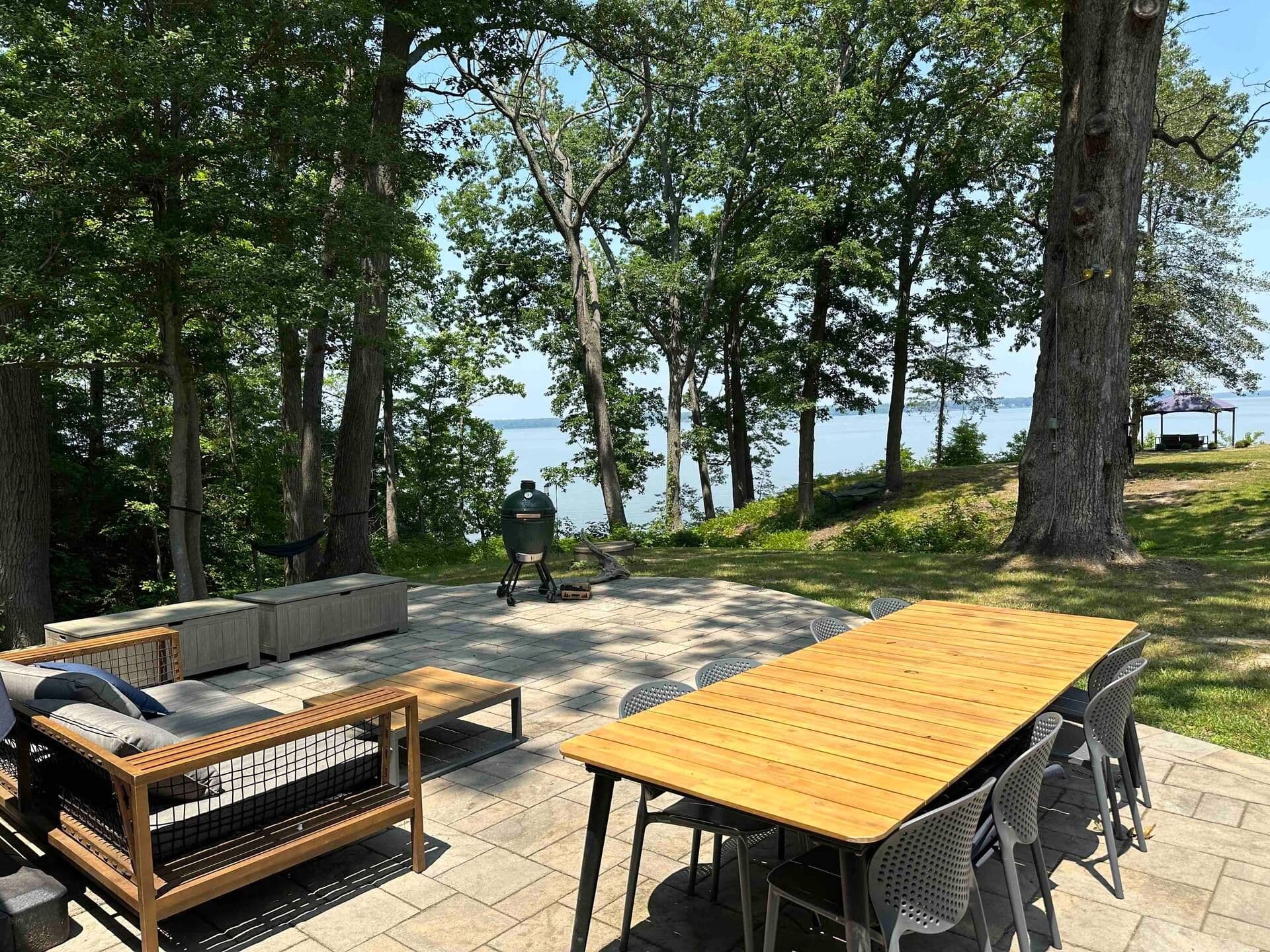Stone patio with outdoor dining, lounge seating, and the Big Green Egg overlooking the Potomac